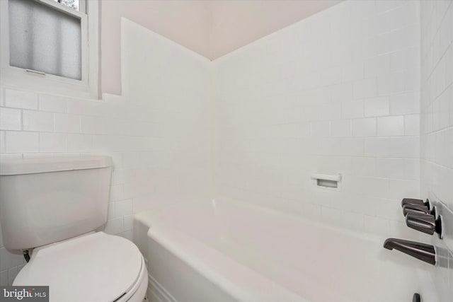 bathroom with tile walls, toilet, and shower / washtub combination