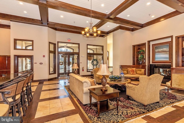 living room with a multi sided fireplace, a towering ceiling, light tile patterned floors, beamed ceiling, and a notable chandelier