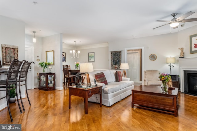 living room featuring ceiling fan with notable chandelier and light hardwood / wood-style flooring