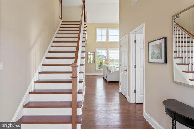 stairway featuring hardwood / wood-style floors and a towering ceiling