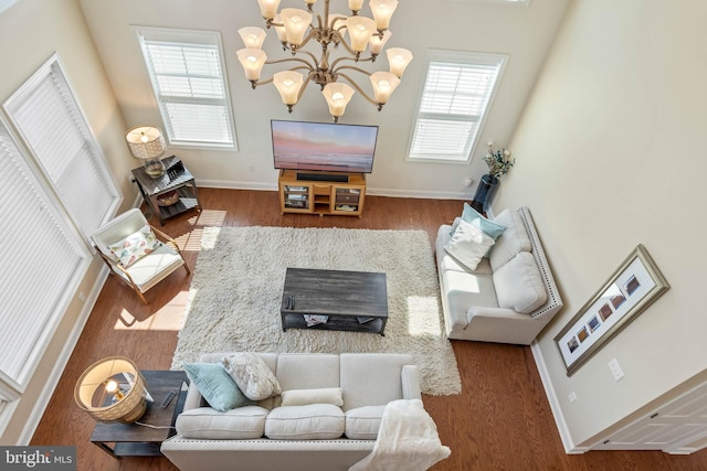 living room with plenty of natural light, wood-type flooring, and an inviting chandelier