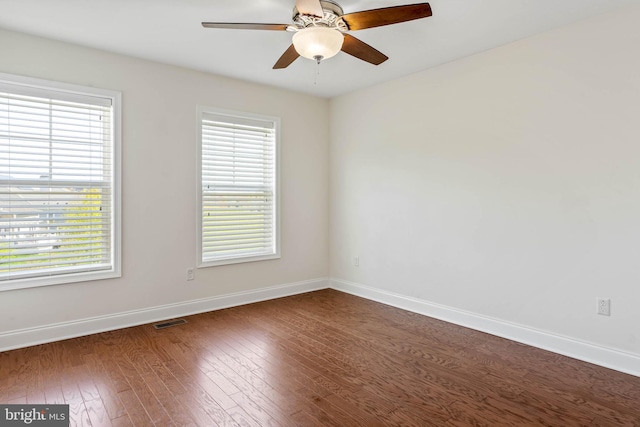 empty room featuring dark hardwood / wood-style floors, ceiling fan, and a wealth of natural light