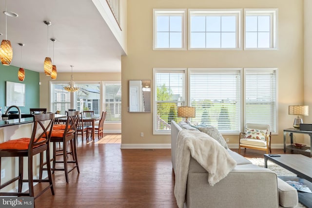 living room featuring a high ceiling, dark hardwood / wood-style flooring, and a healthy amount of sunlight