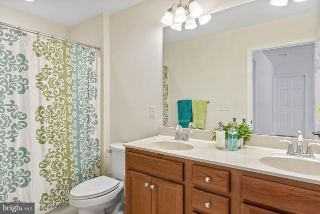 bathroom with a notable chandelier, vanity, and toilet