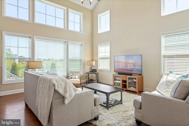 living room featuring dark hardwood / wood-style floors, high vaulted ceiling, and a notable chandelier