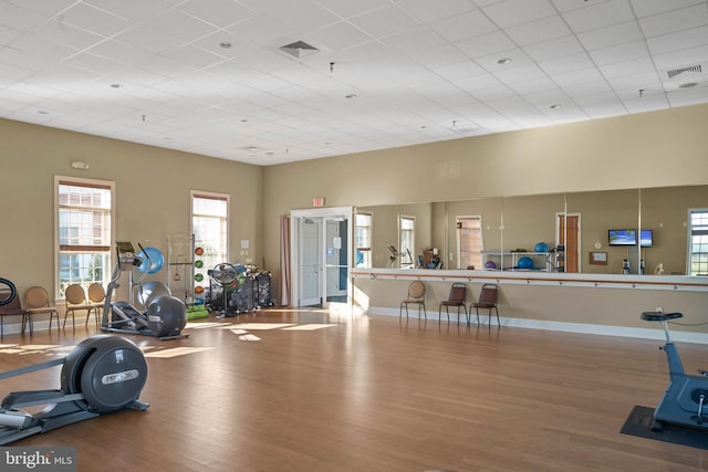 exercise room featuring a high ceiling, light hardwood / wood-style floors, and a drop ceiling