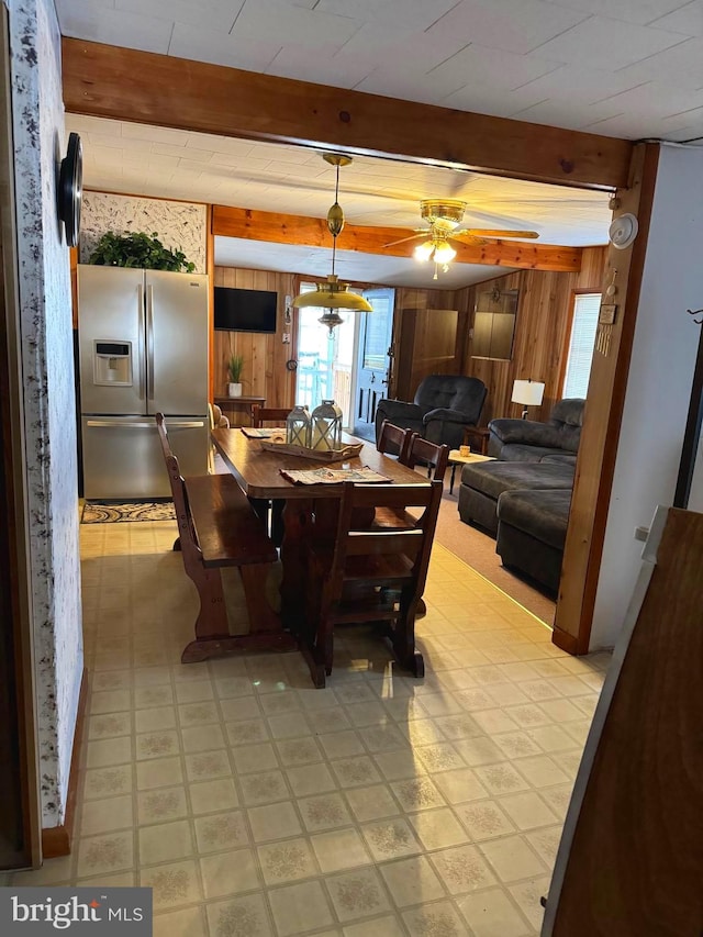 tiled dining room featuring wood walls, beam ceiling, and ceiling fan