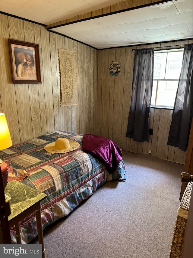 carpeted bedroom featuring wooden walls