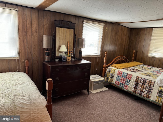 bedroom with wood walls and dark carpet