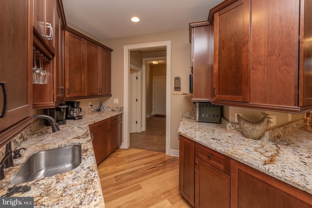 kitchen featuring light hardwood / wood-style floors, sink, and light stone counters