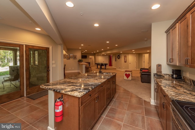 kitchen with range, sink, tile floors, and dark stone counters