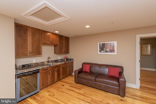 kitchen with sink, dishwasher, dark stone countertops, and light wood-type flooring