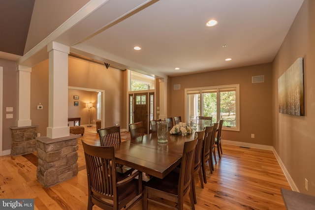 dining area with light hardwood / wood-style flooring, ornate columns, and lofted ceiling