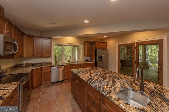 kitchen featuring tile flooring, sink, appliances with stainless steel finishes, and dark stone countertops