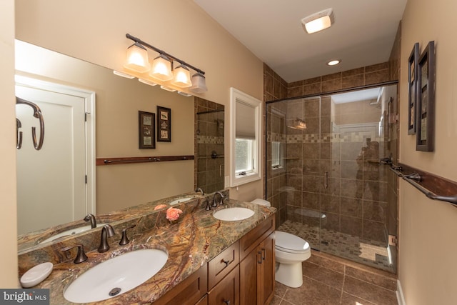 bathroom featuring a shower with door, large vanity, double sink, tile flooring, and toilet