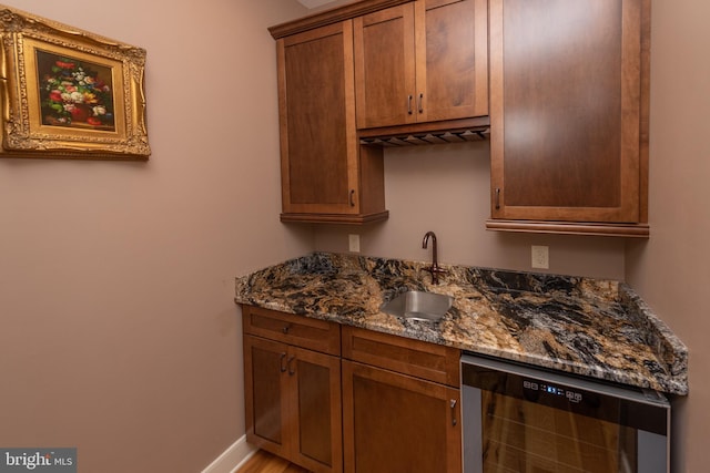 kitchen featuring dark stone countertops, dishwasher, and sink