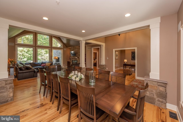 dining area featuring lofted ceiling, light wood-type flooring, and decorative columns