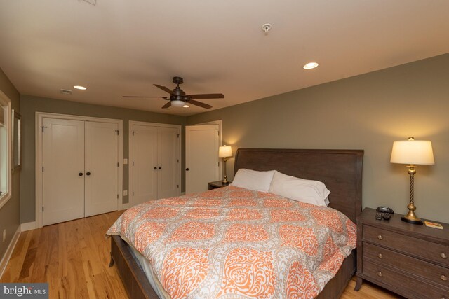 bedroom featuring ceiling fan, light wood-type flooring, and two closets