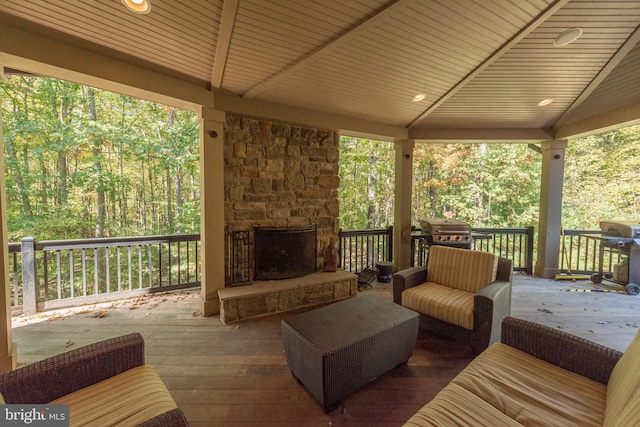 wooden deck with grilling area and a stone fireplace