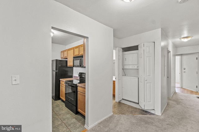 kitchen featuring light carpet, stacked washer / drying machine, and black appliances