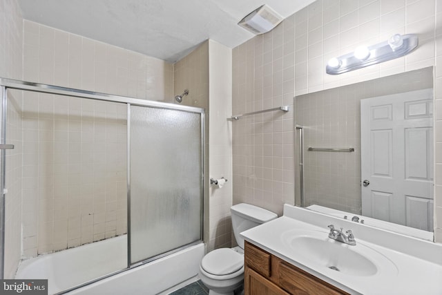 full bathroom with tile walls, oversized vanity, combined bath / shower with glass door, toilet, and tile flooring