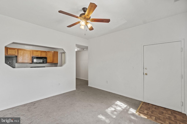 unfurnished living room with ceiling fan and dark parquet flooring