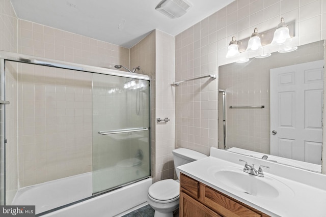 full bathroom with combined bath / shower with glass door, toilet, and vanity with extensive cabinet space