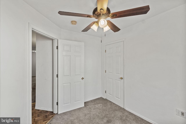 unfurnished bedroom with ceiling fan and dark colored carpet