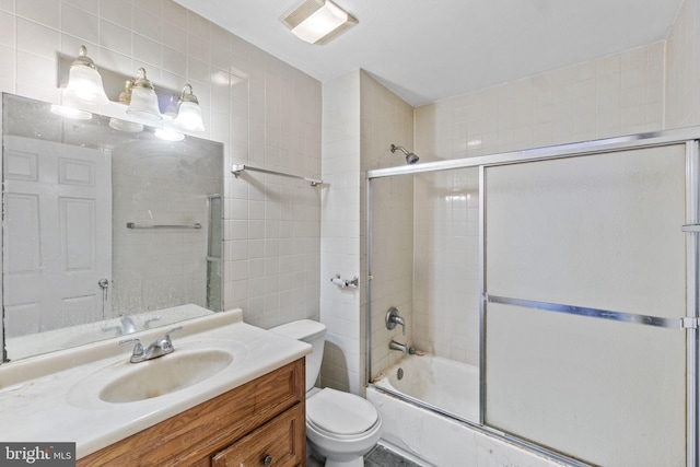 full bathroom featuring combined bath / shower with glass door, vanity, toilet, and tile walls