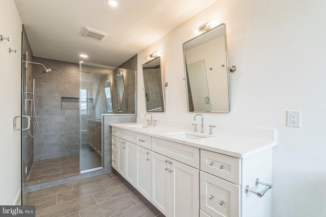 bathroom featuring double vanity, a sink, tile patterned floors, and a shower stall