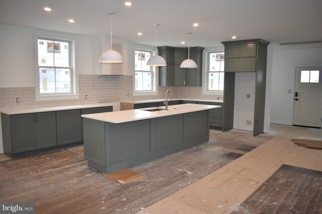 kitchen featuring decorative backsplash, pendant lighting, a sink, recessed lighting, and an island with sink
