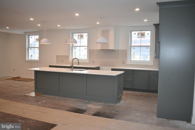 kitchen with decorative backsplash, a kitchen island with sink, recessed lighting, gray cabinets, and a sink