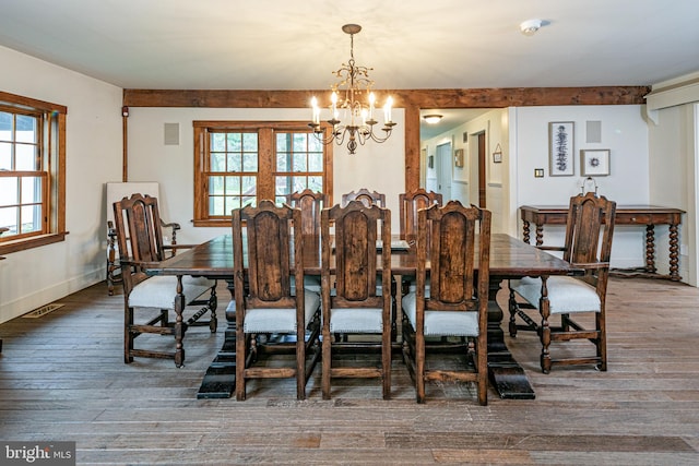 dining space with plenty of natural light, hardwood / wood-style floors, and an inviting chandelier