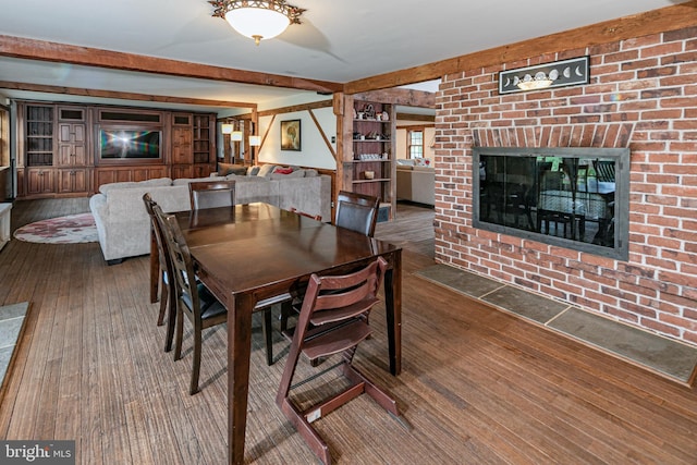 dining area with wood-type flooring, beam ceiling, and a fireplace