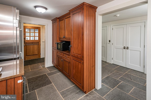 kitchen with stone countertops, dark tile flooring, and high end refrigerator