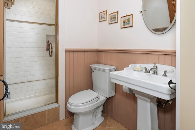 bathroom featuring toilet, a tile shower, and tile flooring