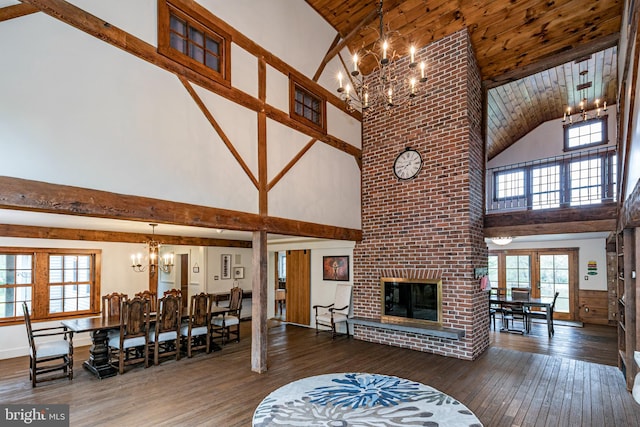 living room with hardwood / wood-style flooring, high vaulted ceiling, a notable chandelier, and a fireplace