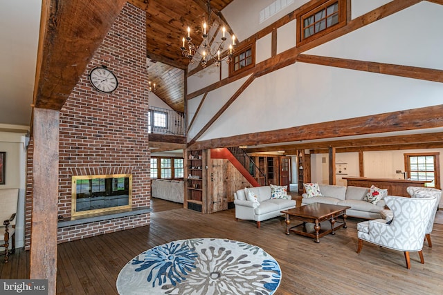 living room with hardwood / wood-style flooring, high vaulted ceiling, a notable chandelier, and a fireplace