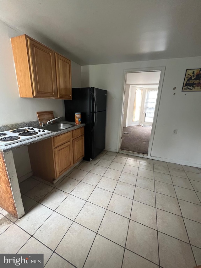 kitchen with sink, white electric cooktop, light tile flooring, and black refrigerator