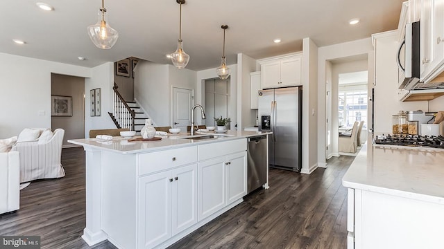 kitchen with white cabinets, appliances with stainless steel finishes, sink, and a kitchen island with sink