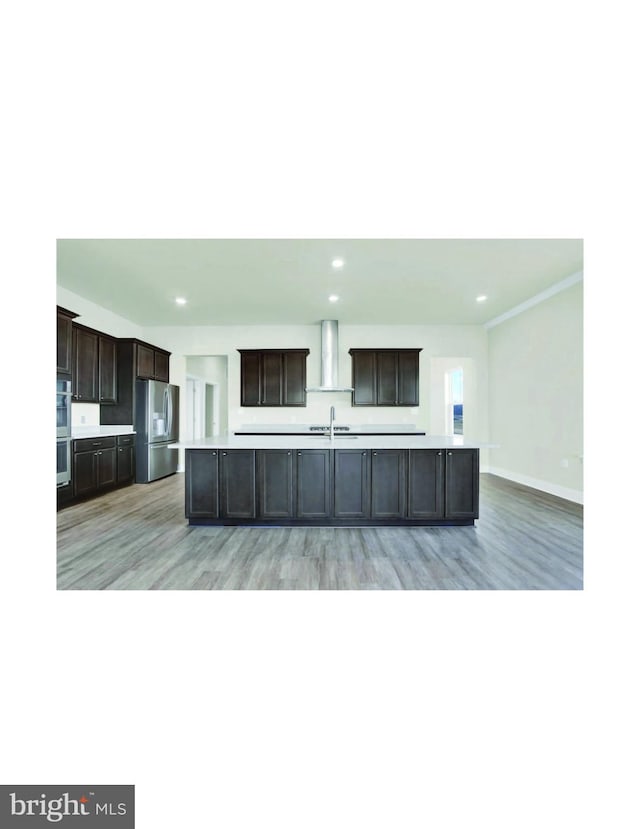 kitchen featuring dark brown cabinets, an island with sink, light wood-type flooring, and stainless steel appliances