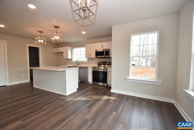 kitchen with appliances with stainless steel finishes, dark wood-type flooring, a healthy amount of sunlight, and white cabinets