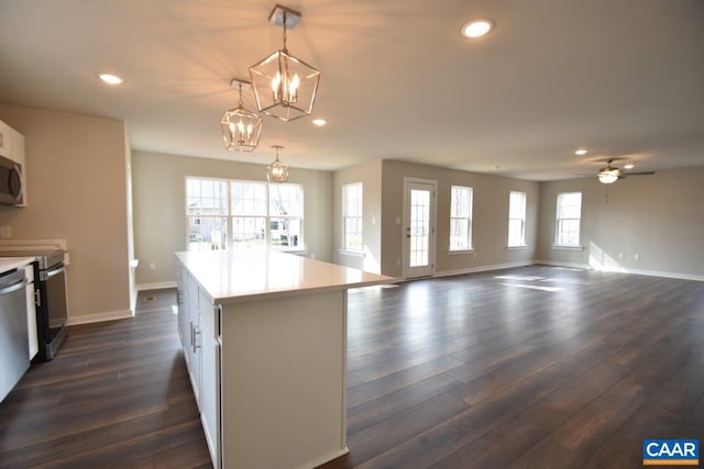 kitchen with decorative light fixtures, white cabinetry, plenty of natural light, dark hardwood / wood-style flooring, and a kitchen island