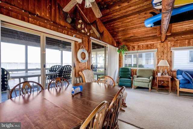 dining area featuring wood walls, high vaulted ceiling, carpet floors, wooden ceiling, and ceiling fan