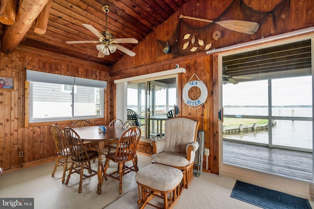 carpeted dining space with lofted ceiling, ceiling fan, a healthy amount of sunlight, and a water view