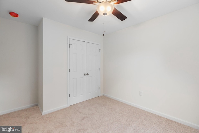 unfurnished bedroom with ceiling fan, a closet, and light colored carpet