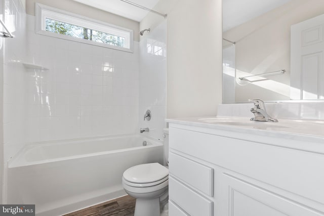 full bathroom with vanity with extensive cabinet space, tiled shower / bath, toilet, and hardwood / wood-style floors