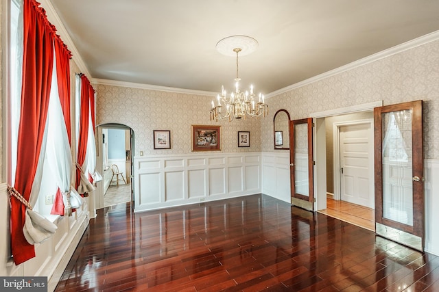 spare room with crown molding, dark hardwood / wood-style flooring, and a notable chandelier