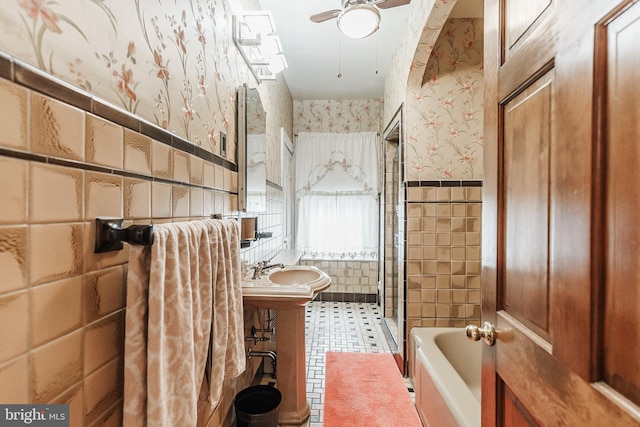 bathroom featuring tiled shower / bath combo, tile floors, tile walls, sink, and ceiling fan