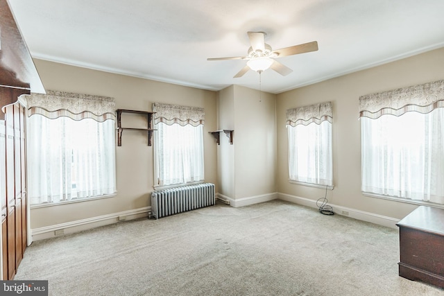 carpeted empty room featuring ceiling fan and radiator heating unit